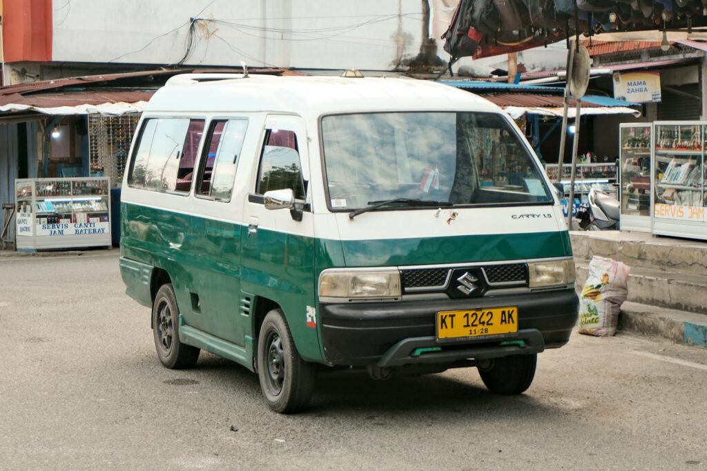 A green and white van driving on a street.